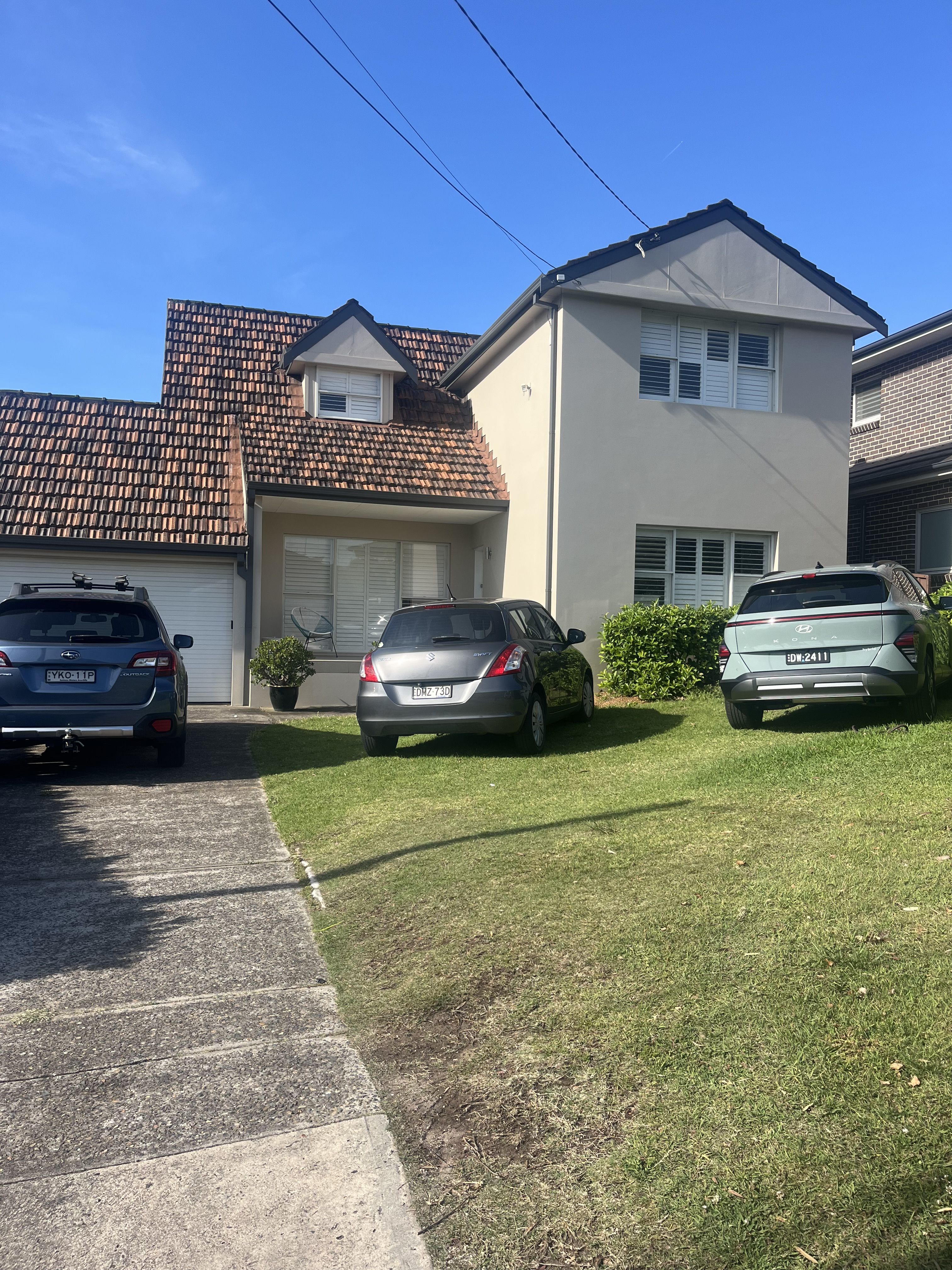 A suburban driveway with four cars parked closely together, suggesting multiple adults living in the same household.