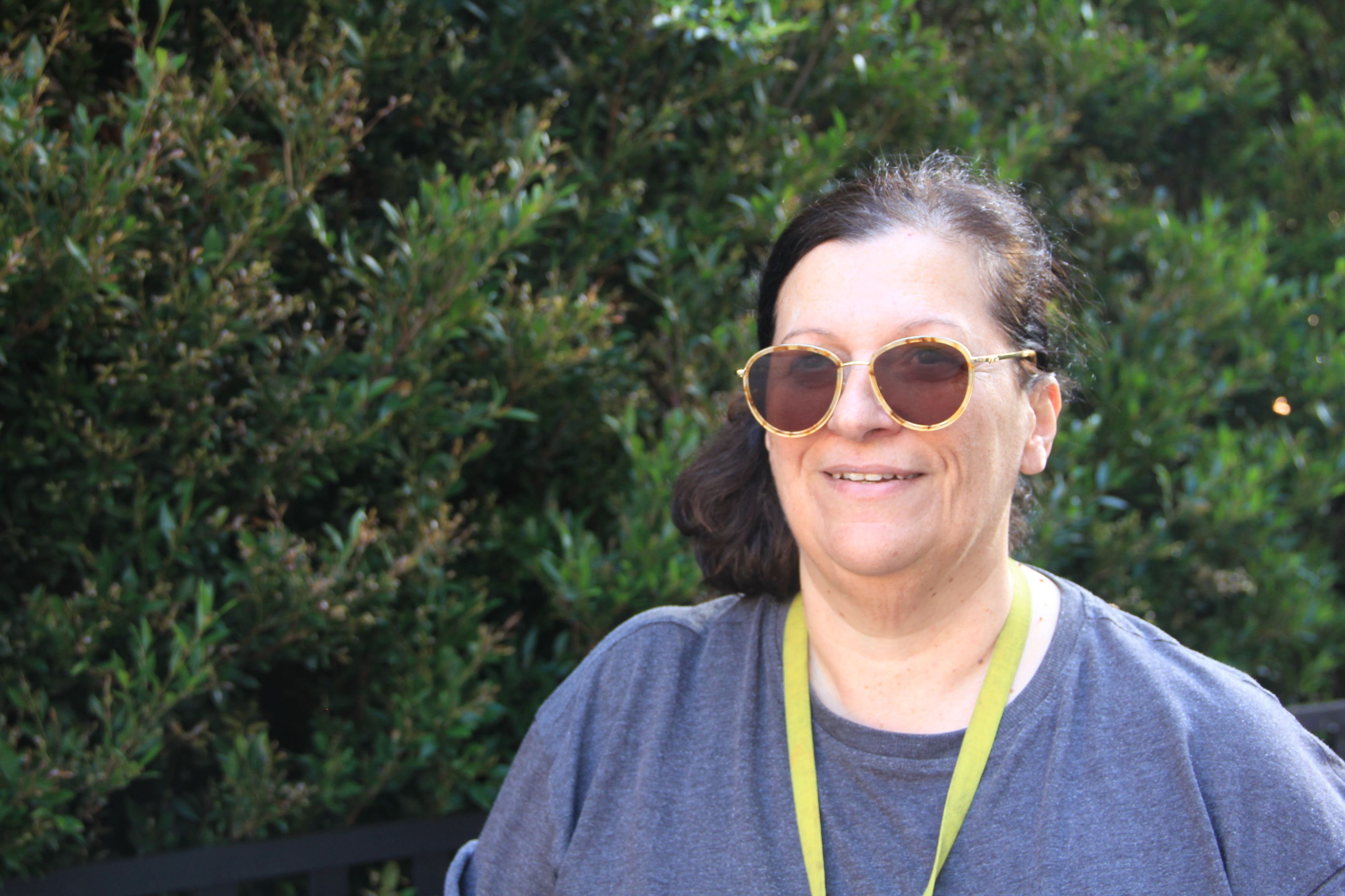 Mid shot of Independent cat rescuer; Annie Georgiou looking off into the distance with a bush in the background